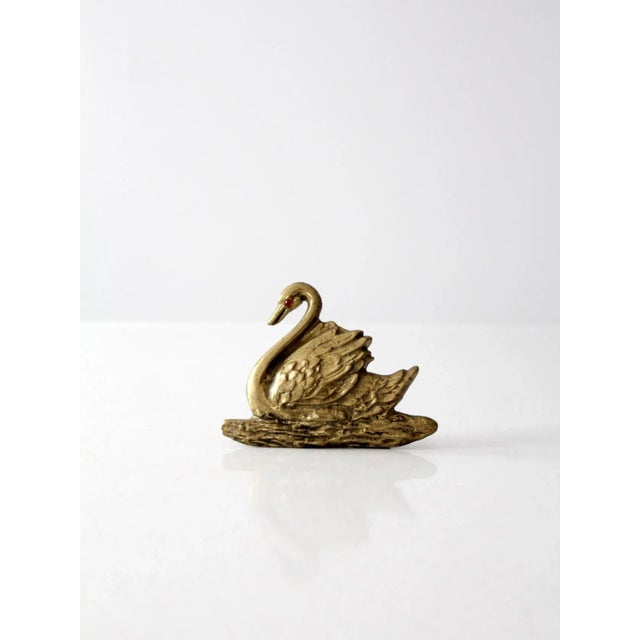 This is a vintage brass swan figure or paper weight. The brass plaque pictures a swan serenely floating on water. A red...