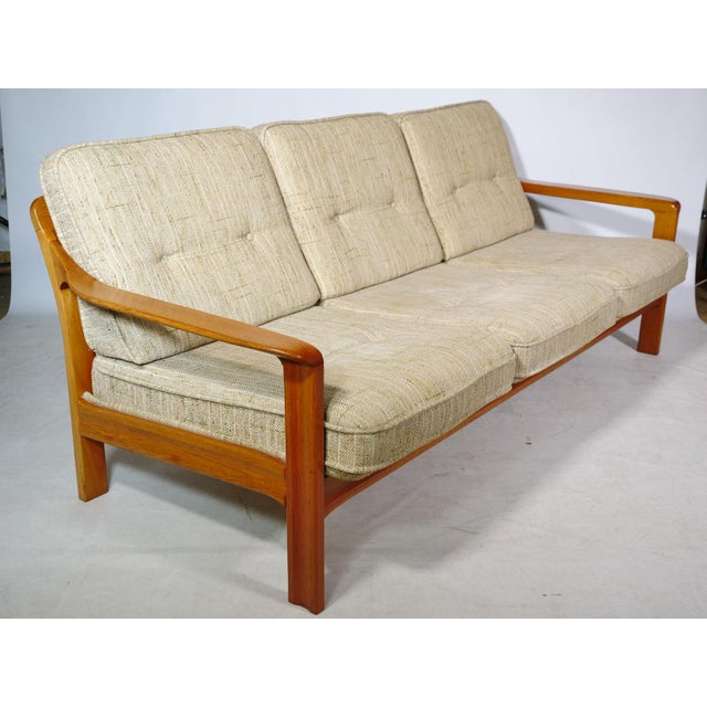 Scandinavian 1970s three-seater sofa made of solid teak. Generously sized with six cushions on a sturdy wooden frame....