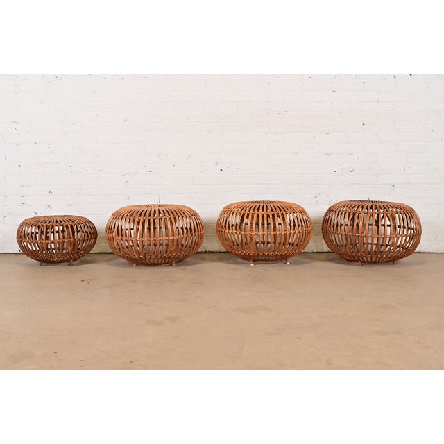 A gorgeous set of four mid-century Organic Modern bent rattan pouf ottomans, footstools, or side tables Designed by Franco...