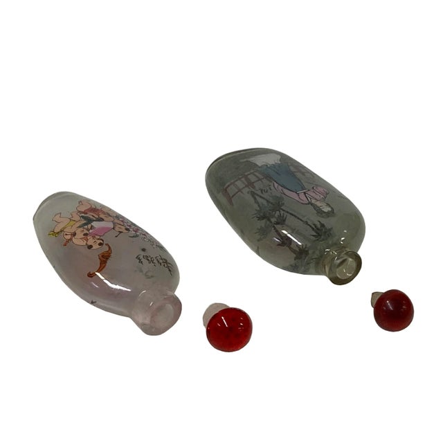 These two Chinese snuff bottles are made of glass, the surface is inside painted with oriental scenery people graphics....