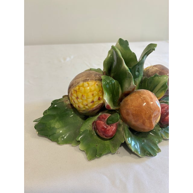 A beautifully handcrafted vintage Capodimonte porcelain taper candle holder featuring an abundant harvest arrangement of...