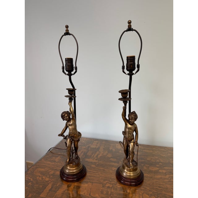 Bring timeless European elegance into your home with this exceptional pair of vintage French-style brass putti cherub...