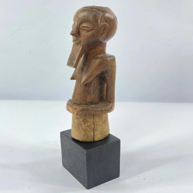 This hand-carved wooden figure is attributed to the Kusu people of the Democratic Republic of the Congo, a region renowned...