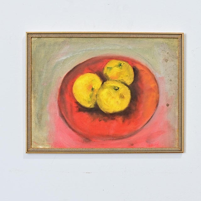 A mid-20th century French oil painting on canvas of three green apples in a fiery red bowl, the composition is a...