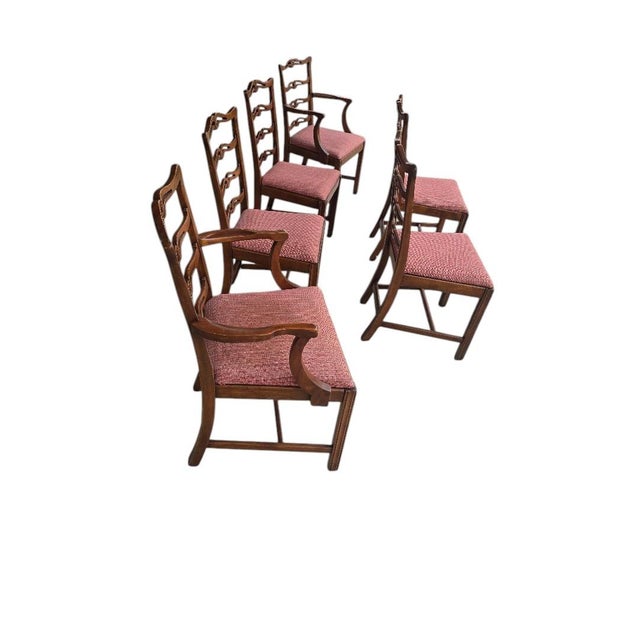 A handsome set of six vintage dining chairs featuring an elegant pierced ladderback design, warm wood finish, and...