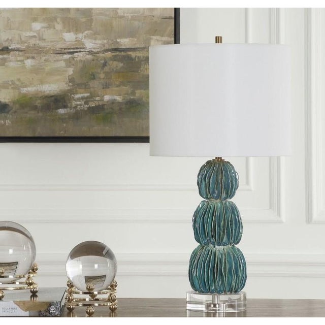 The Bonaire lamp showcases a captivating ceramic base of stacked spheres, each adorned with carefully folded and layered...