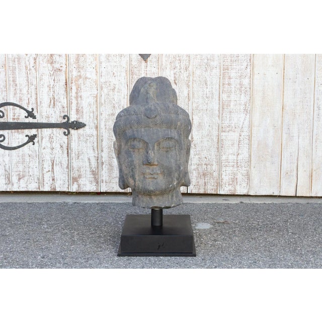 An antique stone statue of lovely proportions, this buddha head is hand-carved out of a single slab of stone. This Buddha...