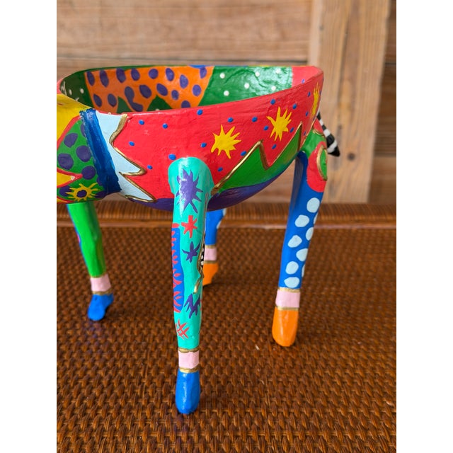 A vibrant hand-painted Alebrije-style folk art giraffe planter featuring bold geometric patterns, playful dots, and...