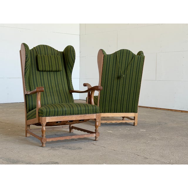 A substantial and imposing pair of Danish wingback armchairs constructed in solid oak and upholstered in their original...