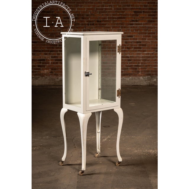 Tall porcelain-enamel and steel dental cabinet on cabriole metal legs, originally designed for organizing instruments,...