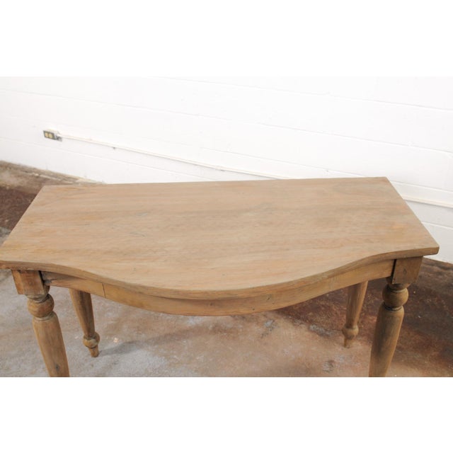 A charming French wooden console table, with bow-front design, from the late 19th century. This antique table from France...