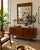 Striking 1970s Mid-Century Modern wall mirror featuring a warm walnut-finished wood frame and a distinctive decorative...