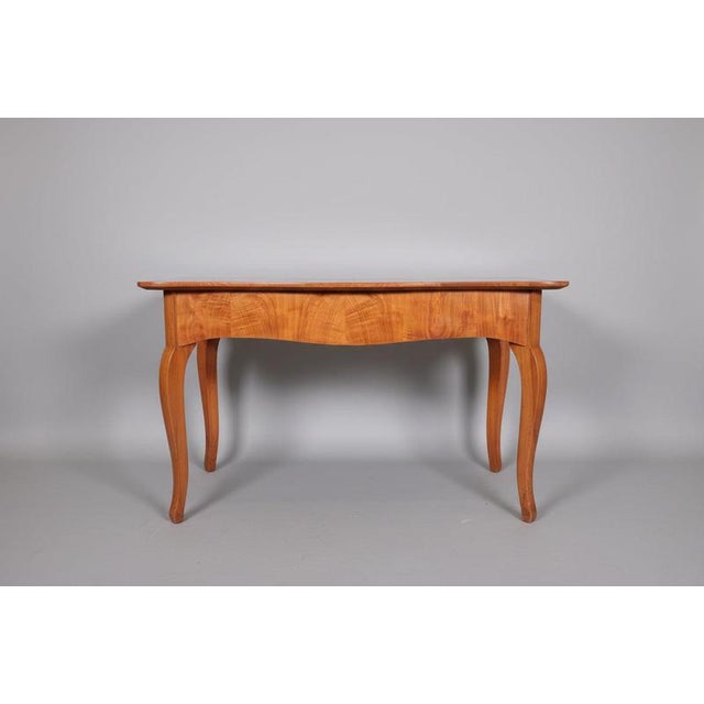 This elegant biedermeier table from around 1820 impresses with its clean lines, warm cherry wood, and fine craftsmanship....