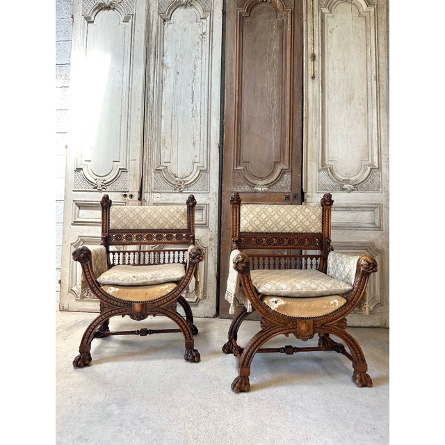 Pair of Renaissance-style walnut ceremonial armchairs, circa 1880. Curule-shaped, they feature carved faun heads on the...