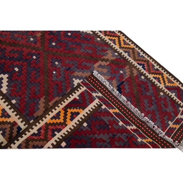 Beautiful kilim handmade wool runner with a red field. This Vintage flatweave rug has orange, blue, and brown accents...