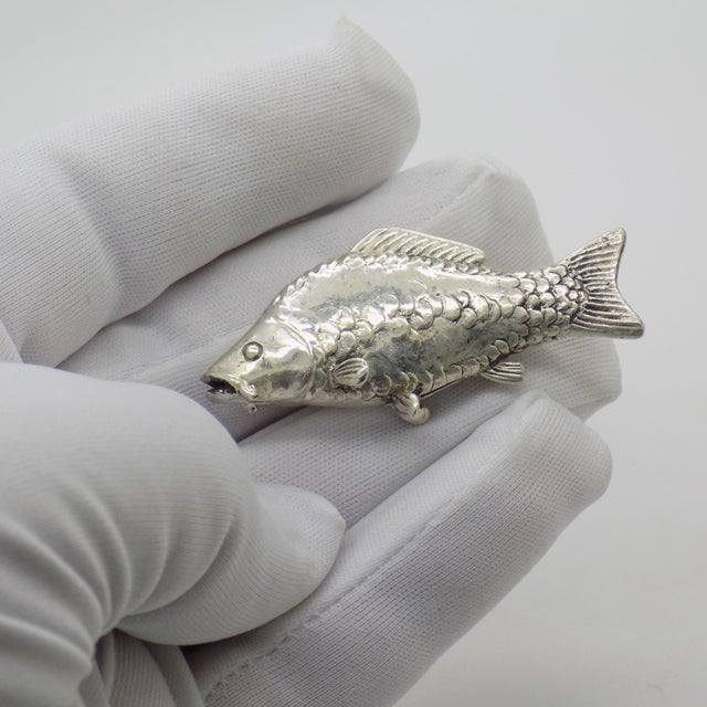 Distinguished by its substantial feel and poetic aquatic theme, this rare vintage silver figurine depicts a detailed carp...