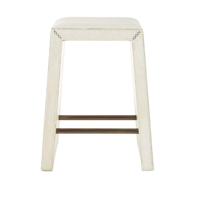 Crafted of white hair-on-hide, this backless counter stool is a tactile delight. A mitered whipstitch creates a racing...
