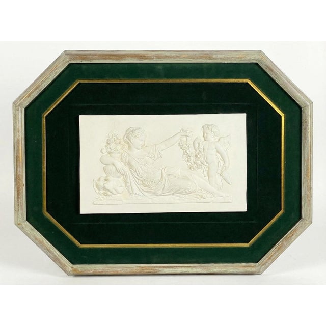 A beautifully framed neoclassical plaster relief depicting a reclining maiden offering a garland of flowers to a cherub....