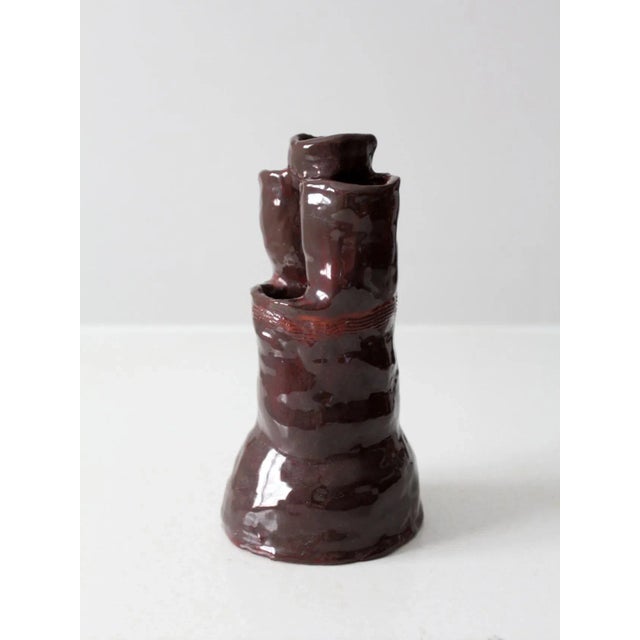 This vintage studio pottery vase features an expressive, free-form silhouette with a rich, dark reddish-brown glaze. Hand-...