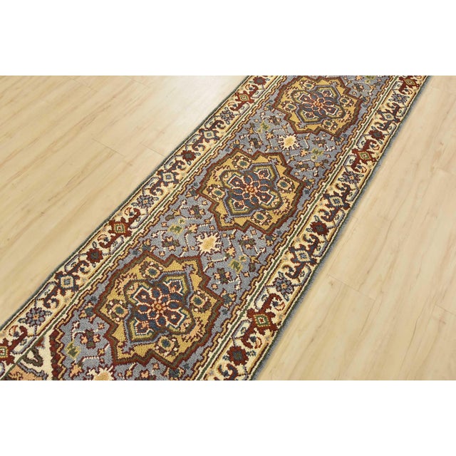 A traditional tribal Heriz runner hand-knotted with an all-wool pile on a cotton foundation. This oriental rug features...