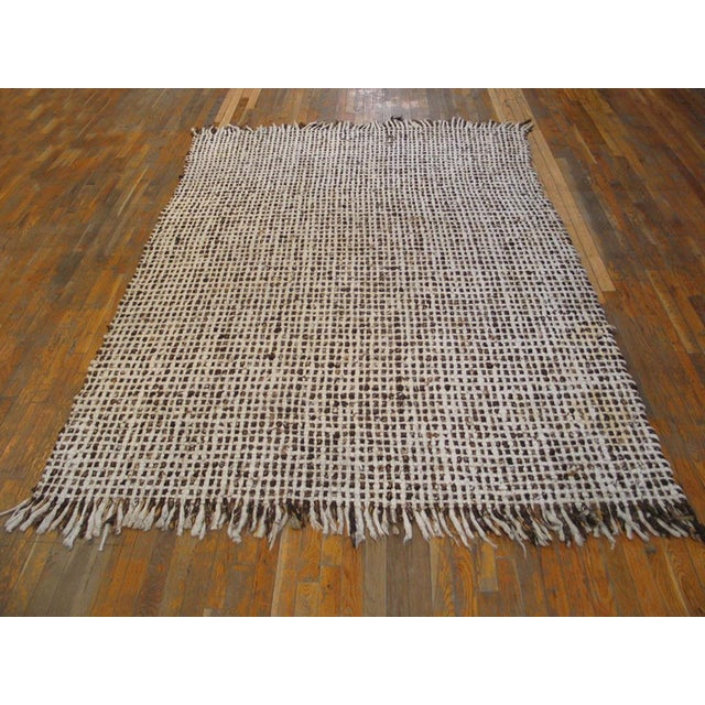 A border less, clearly artisanal ecru close rectangular grid work shows tufts and bits in autumnal shades and totally...