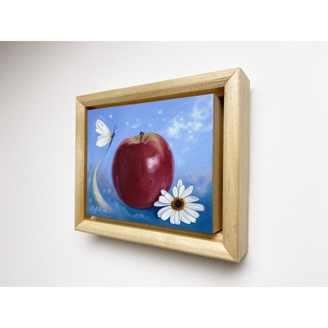 This oil painting features a luscious red apple, accompanied by delicate daisies and a butterfly, all set against a soft...