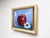 This oil painting features a luscious red apple, accompanied by delicate daisies and a butterfly, all set against a soft...