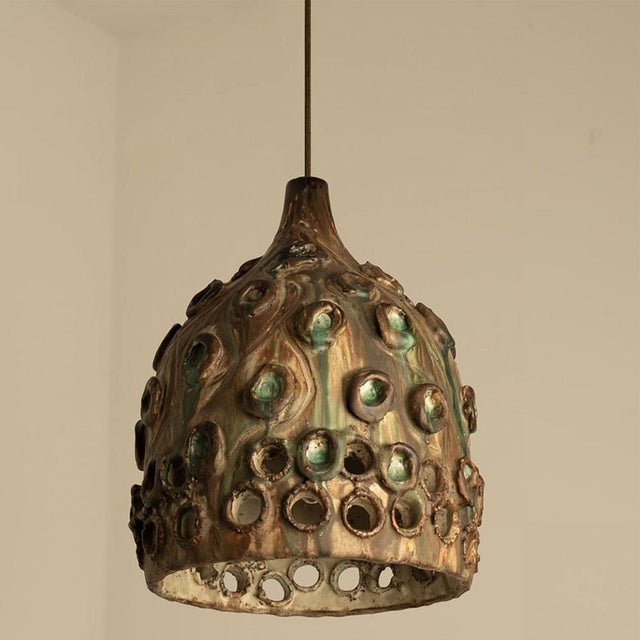 Stylish ceramic pendant light made in denmark. The lamp is made of green and brown ceramic and has a pattern of holes in...