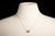 A delicate 14K gold chain necklace featuring a cluster of five emerald-cut green tourmaline gemstones interspersed with...