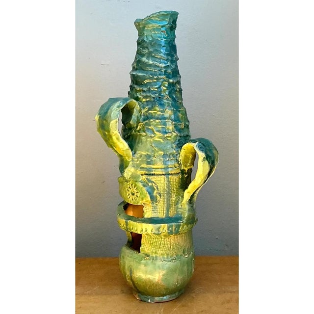 This vintage ceramic vase is a bold, sculptural piece of studio pottery, built as a tall, tapering vessel with a stacked,...