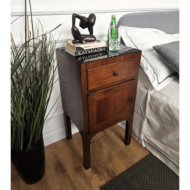 Very elegant and refined Italian 1950s Mid-Century Modern pair of bedside tables with black glass top, one drawer, central...