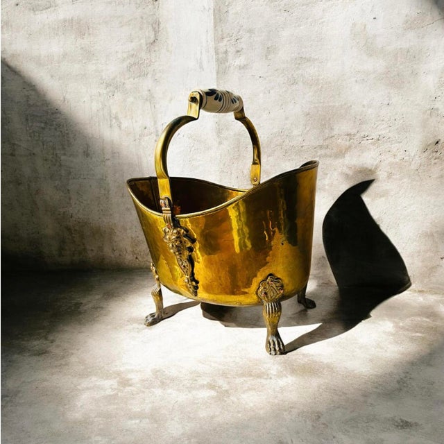This is a vintage brass coal scuttle bucket with lion head details and claw feeT