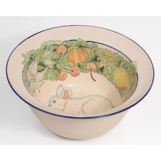 A Davila Brodsky 12" x 5.75" art pottery hand painted bowl featuring a central rabbit surrounding by a bounty of fruit and...