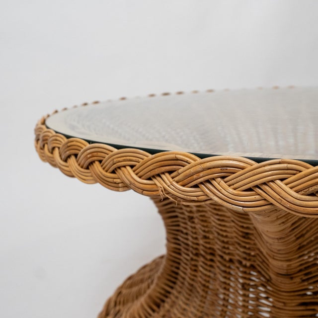 tylish 1970s coastal braided rattan coffee table featuring a distinctive hourglass form and a fitted glass top. The...