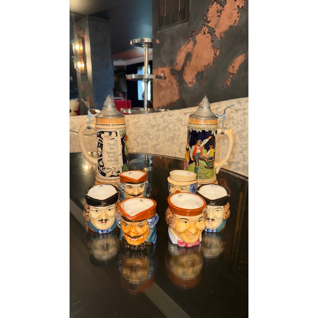 This vintage collection includes six hand-painted ceramic Toby head mugs and two traditional German-style beer steins with...