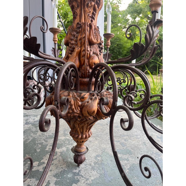 Expressive 1940’s country French style chandelier. Hand carved with scrolling wrought iron arms extending from the center...
