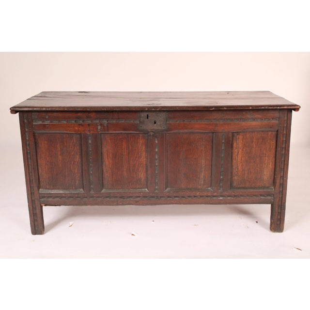English oak trunk, 18th century. With a two board hinged oak top with molded front and side edges, a four panel front,...