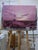 This oil on linen painting depicts a tranquil, expansive landscape at dusk, dominated by soft pink and purple hues that...