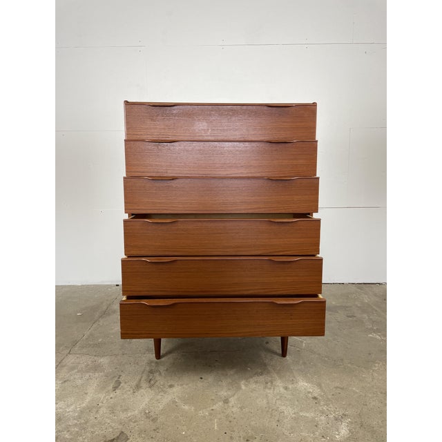 Elegant mid-century modern teak dresser featuring clean lines and beautifully integrated sculpted drawer pulls. The warm...