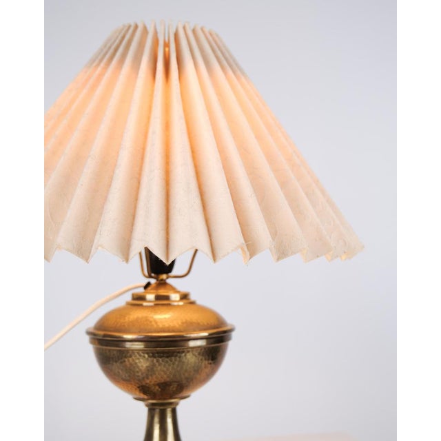 Table lamp made in brass with a white lampshade from the 1930s. The lamp features a simple design with a round base and...