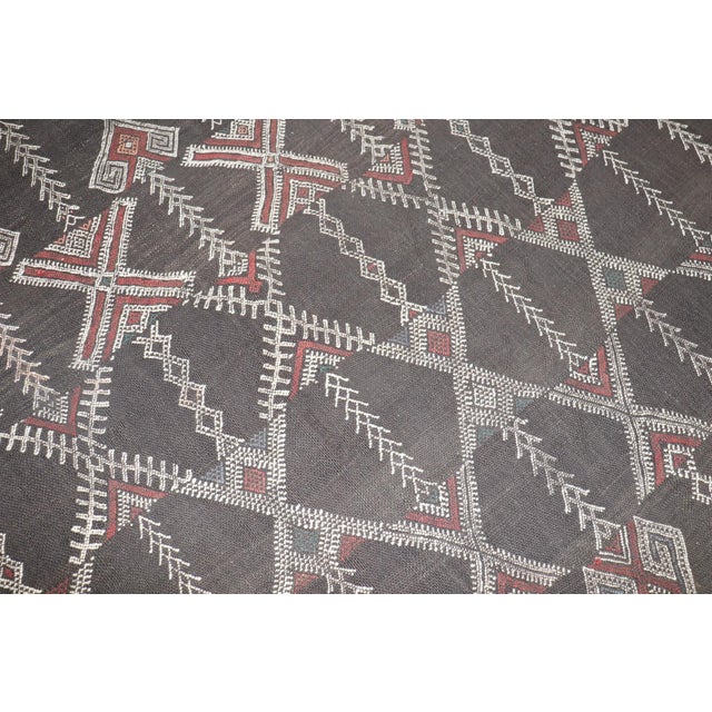A mid 20th century Moroccan Kilim with a large scale geometric design on a charcoal ground