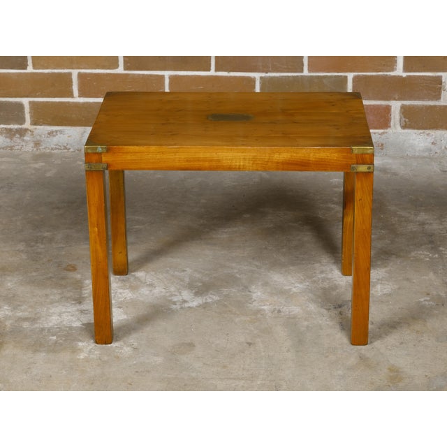An English Campaign yew wood side table from circa 1920 with brass accents and straight legs. This English Campaign yew...