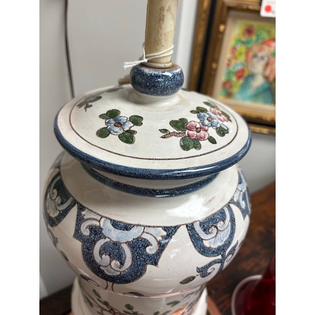 This elegant vintage Chinoiserie table lamp features a striking ginger jar-style ceramic base adorned with intricate blue,...