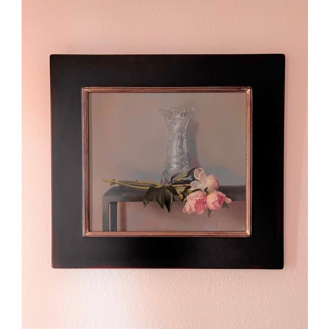 This oil on panel artwork features a delicate arrangement of peonies resting beside an intricately designed crystal vase....