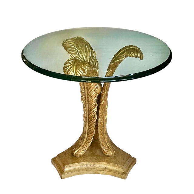 A 3/4” glass top with ovolo edge rests atop a gilded base featuring three swirling ostrich plumes separated by an orb at...