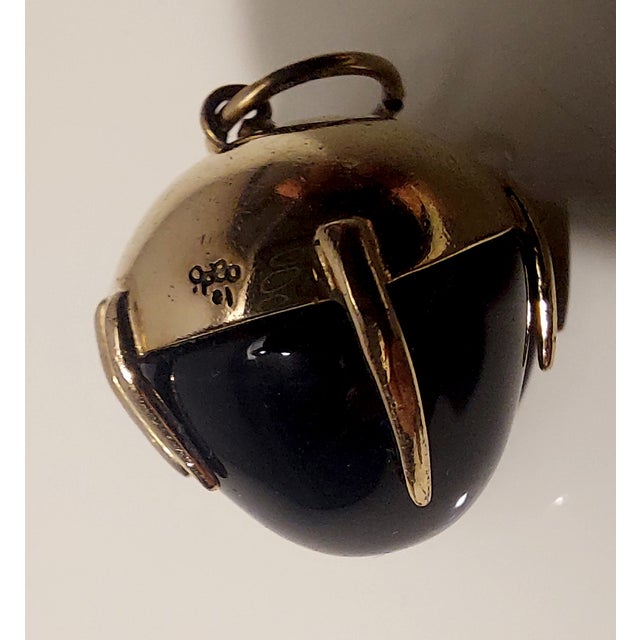 18K yellow gold pendant with black onyx and two hallmarks. It weighs just over 9 grams and measures approximately 2 cm. It...