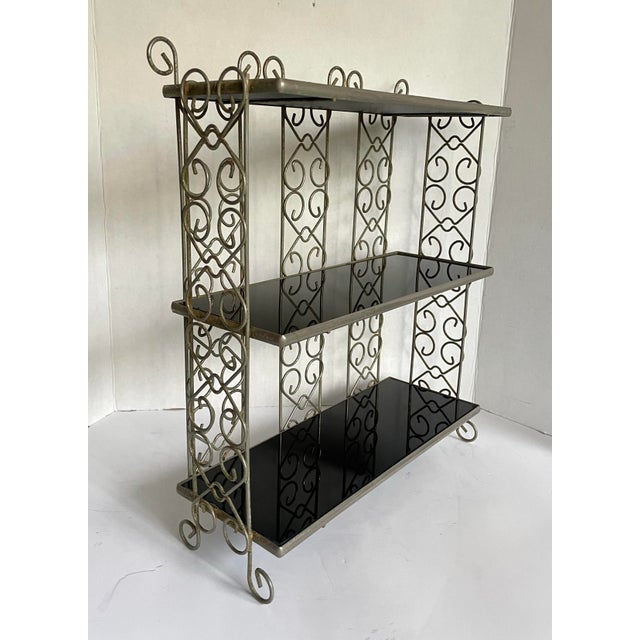 Dating to the mid-20th century, this stylish three-tier display shelf pairs a silver-tone metal frame with glossy black...