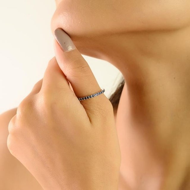 This elegant full eternity band ring features round-cut blue sapphires totaling approximately 0.53 carats, delicately set...