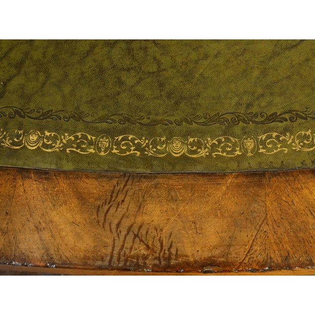 An English oval mahogany table from the 19th century, with green leather top, gilt and tooled arabesques, turned legs and...