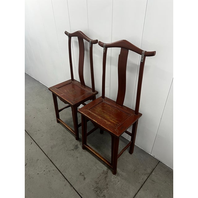 A matched pair of vintage Chinese-style yoke-back side chairs, crafted in hardwood and dating to the mid-20th century. The...